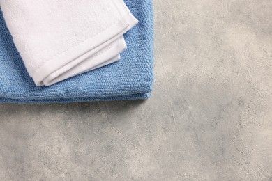 Photo of Soft folded terry towels on light gray textured background, top view. Space for text