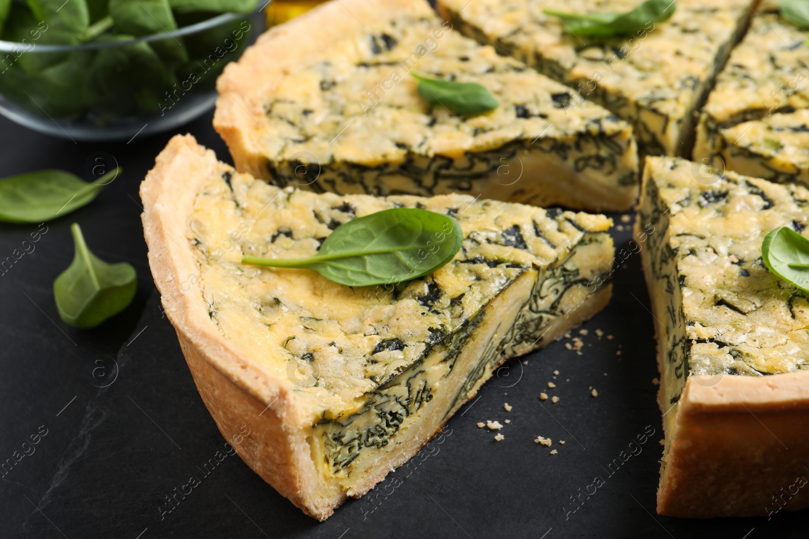 Photo of Cut delicious spinach pie on slate plate, closeup
