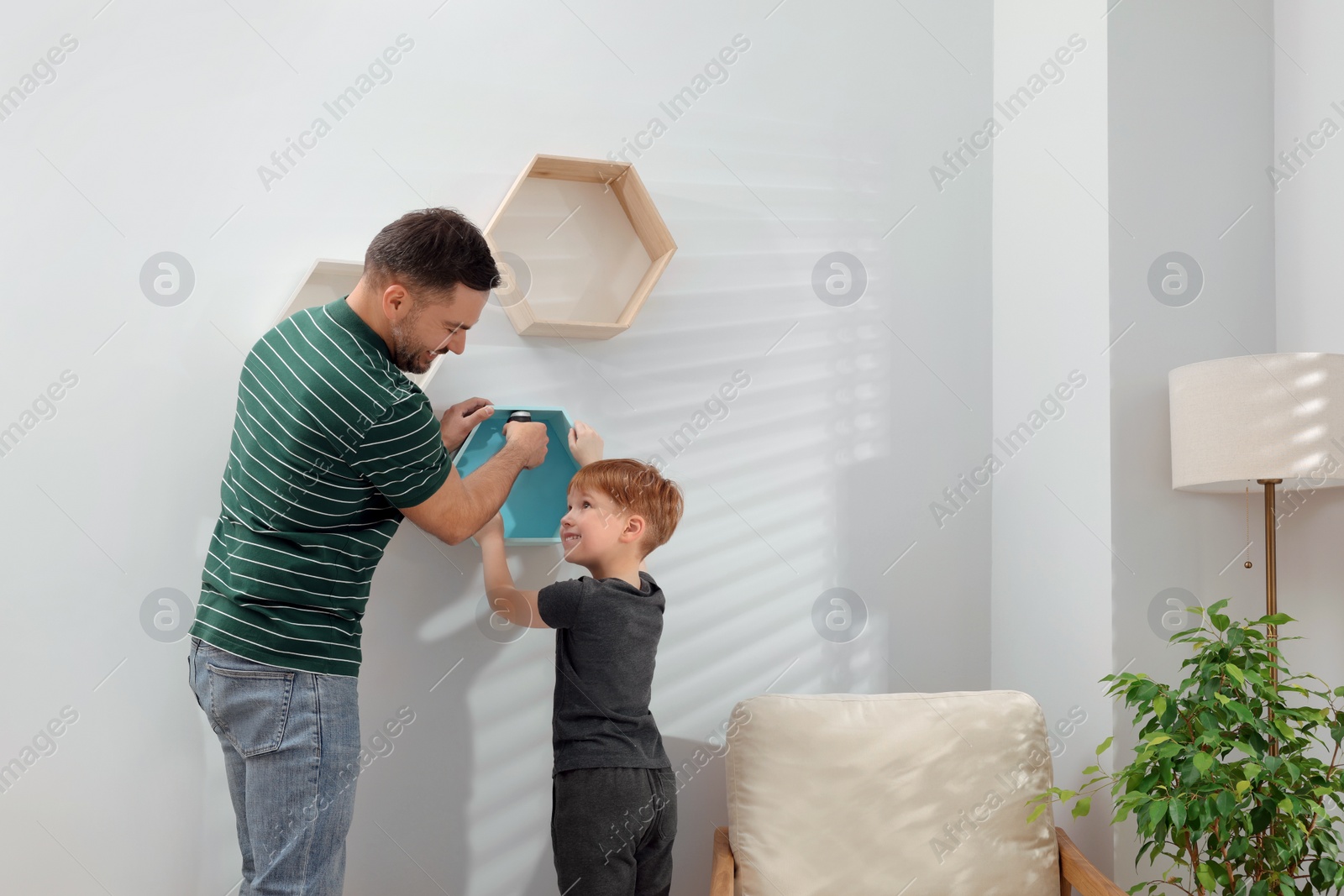 Photo of Father and son installing shelves on wall at home. Repair work
