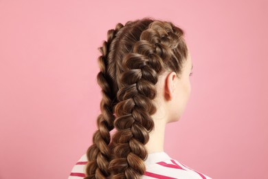 Woman with braided hair on pink background, back view