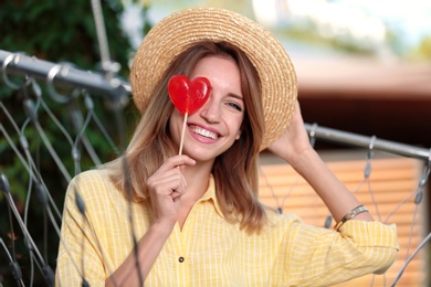 Young woman with candy relaxing in hammock chair outdoors