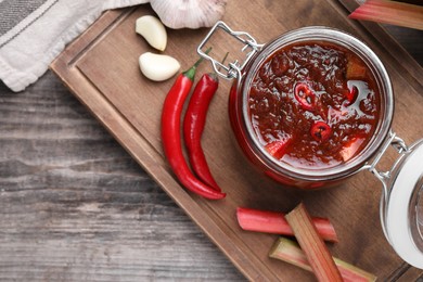 Tasty rhubarb sauce and ingredients on wooden table, top view. Space for text