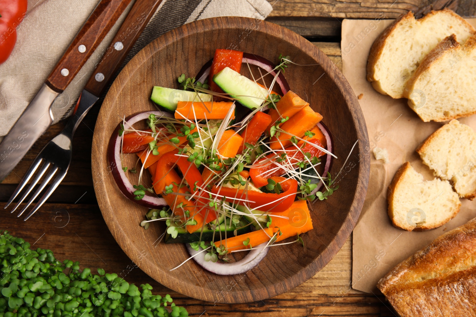 Photo of Salad with fresh organic microgreen in bowl on wooden table, flat lay