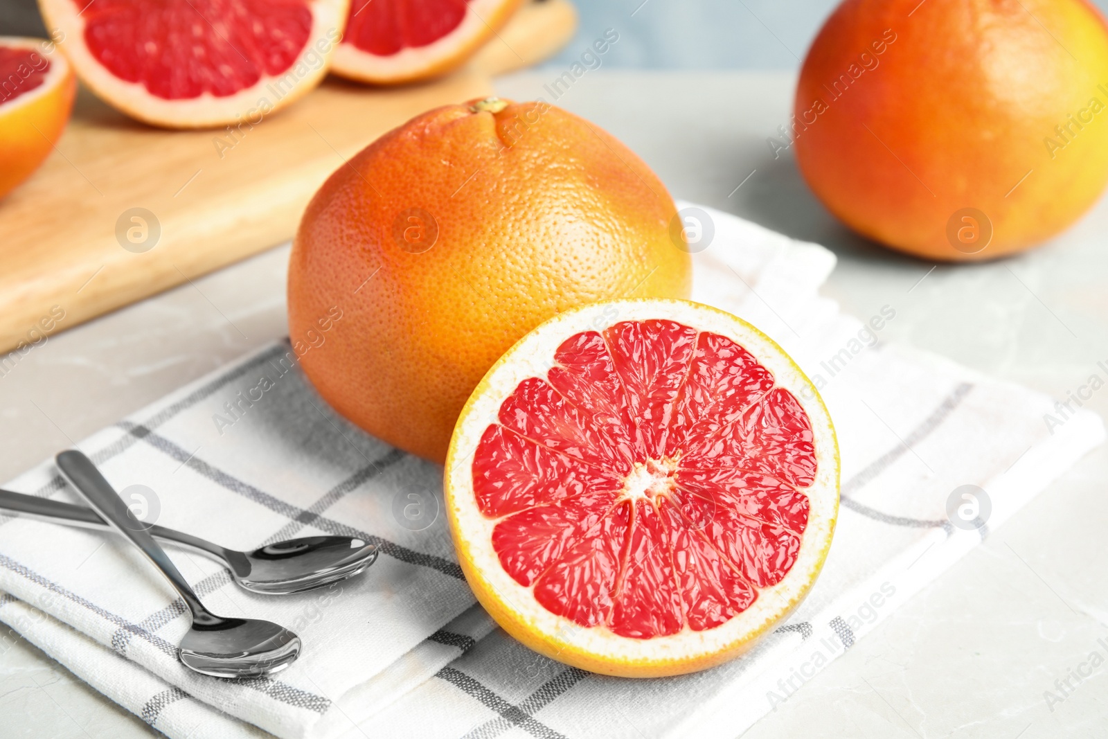 Photo of Fresh grapefruits and dessert spoons on table