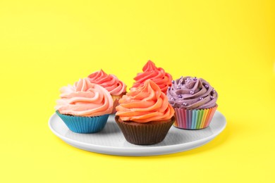 Photo of Delicious cupcakes with bright cream on yellow background