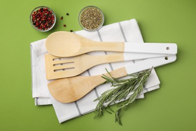 Set of wooden kitchen utensils and spices on green background, flat lay
