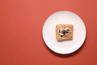 Photo of Toast with tasty nut butter, blueberry and cashews on coral background, top view. Space for text