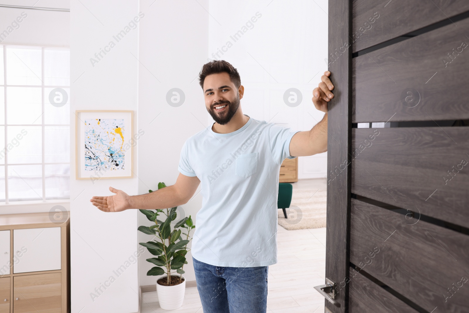 Photo of Happy man welcoming near door. Invitation to come indoors