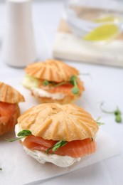 Delicious profiteroles with cream cheese and salmon on white table, closeup