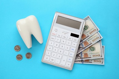 Photo of Ceramic model of tooth, money and calculator on light blue background, flat lay. Expensive treatment