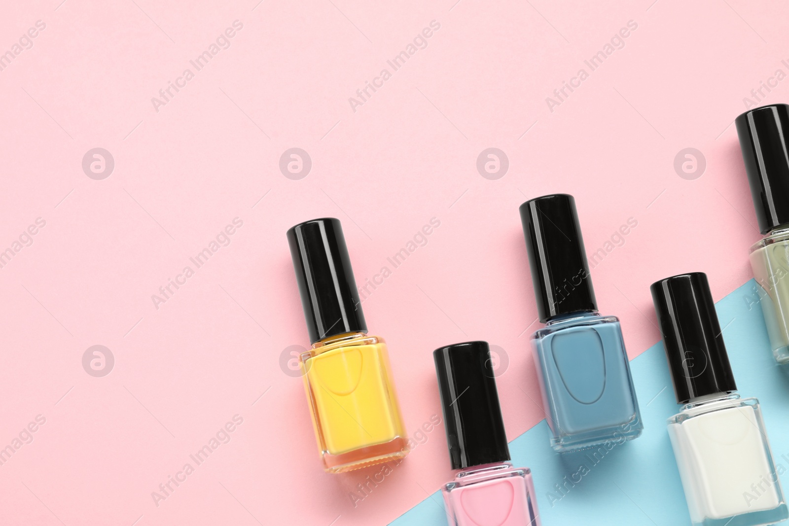 Photo of Bright nail polishes in bottles on color background, flat lay. Space for text