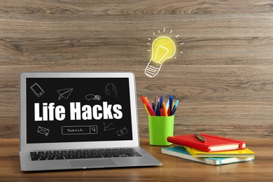 Image of Laptop with words Life Hacks and drawings on screen. Workplace with computer and stationery on wooden table. Lamp bulb illustration near device symbolizing idea