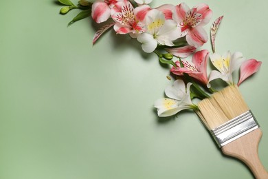 Photo of Composition with painting brush and beautiful alstroemerias on green background, top view. Space for text