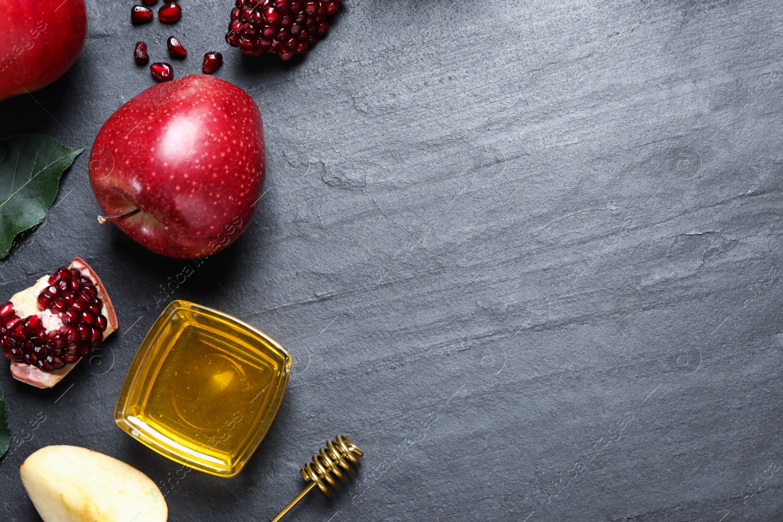 Photo of Honey, apples and pomegranates on black table, flat lay with space for text. Rosh Hashanah holiday