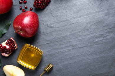 Photo of Honey, apples and pomegranates on black table, flat lay with space for text. Rosh Hashanah holiday