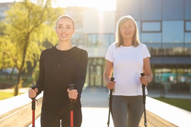 Photo of Happy women practicing Nordic walking with poles outdoors on sunny day