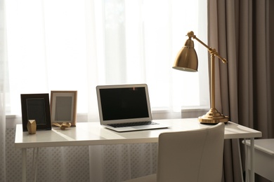 Stylish workplace with laptop on table in office