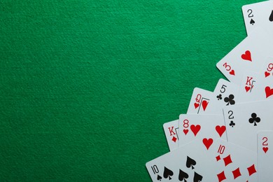 Photo of Many different playing cards on green table, flat lay. Space for text