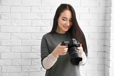 Female photographer with professional camera near brick wall