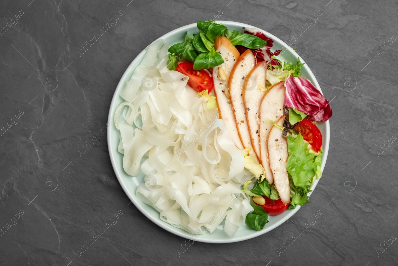 Photo of Tasty cooked rice noodles with chicken and vegetables on black table, top view