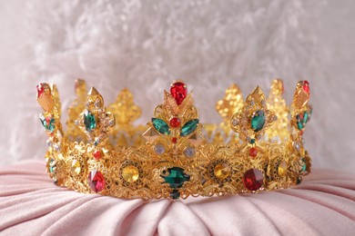 Beautiful golden crown with gems on pink cloth
