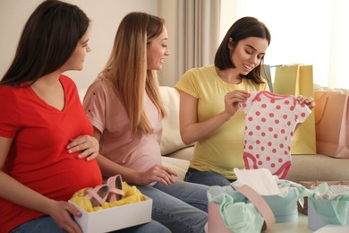 Happy pregnant women spending time together in living room after shopping