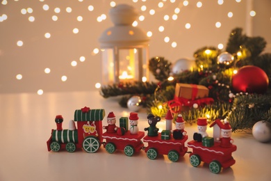 Photo of Toy train and Christmas decor on table against blurred lights