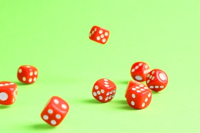 Photo of Many red game dices falling on green background