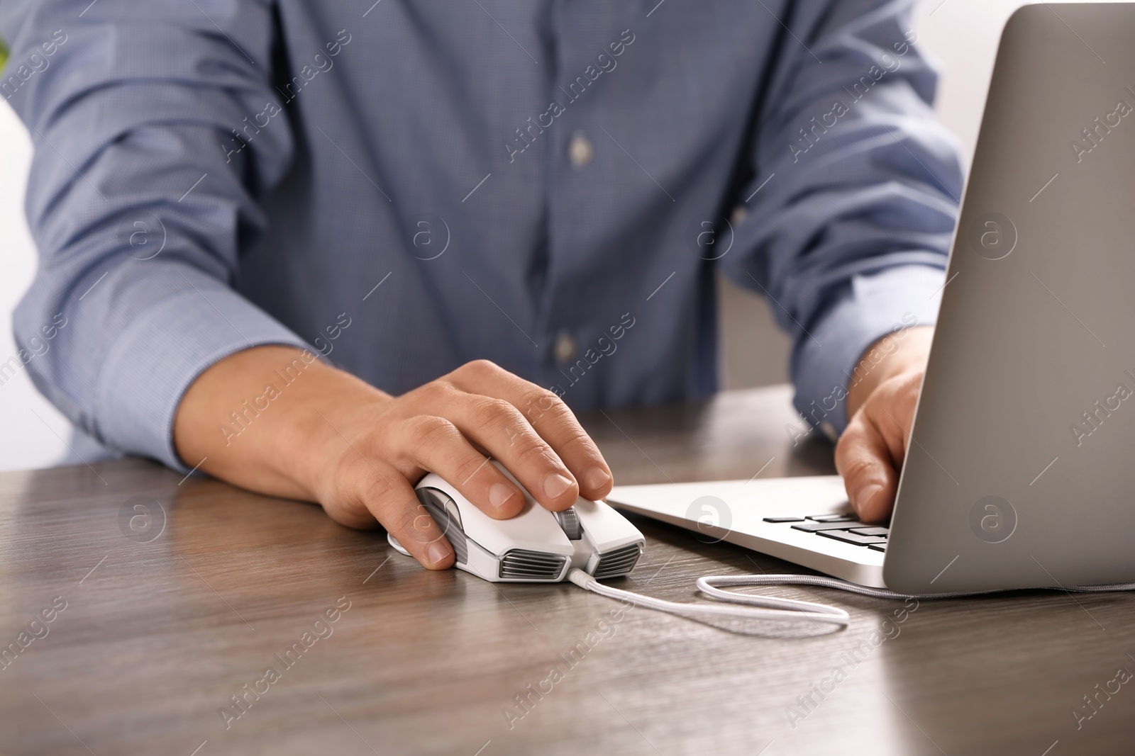 Photo of Man using computer mouse with laptop at table, closeup