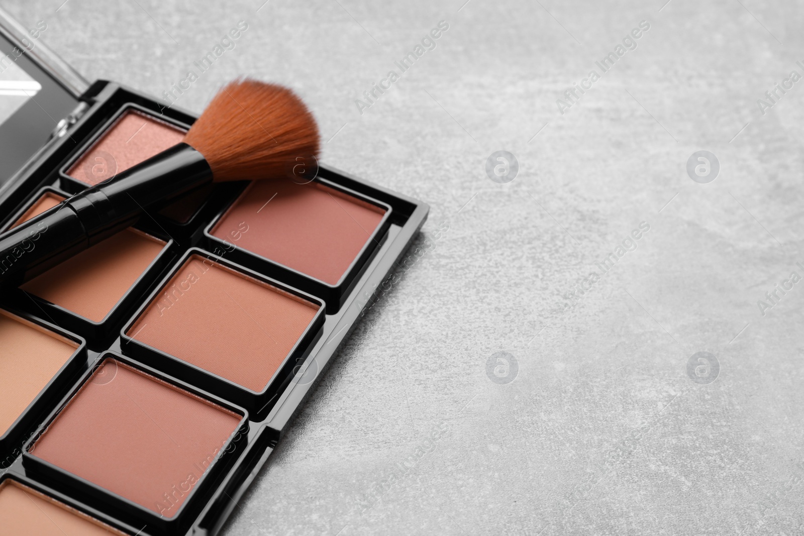 Photo of Contouring palette and brush on light gray background, closeup with space for text. Professional cosmetic product