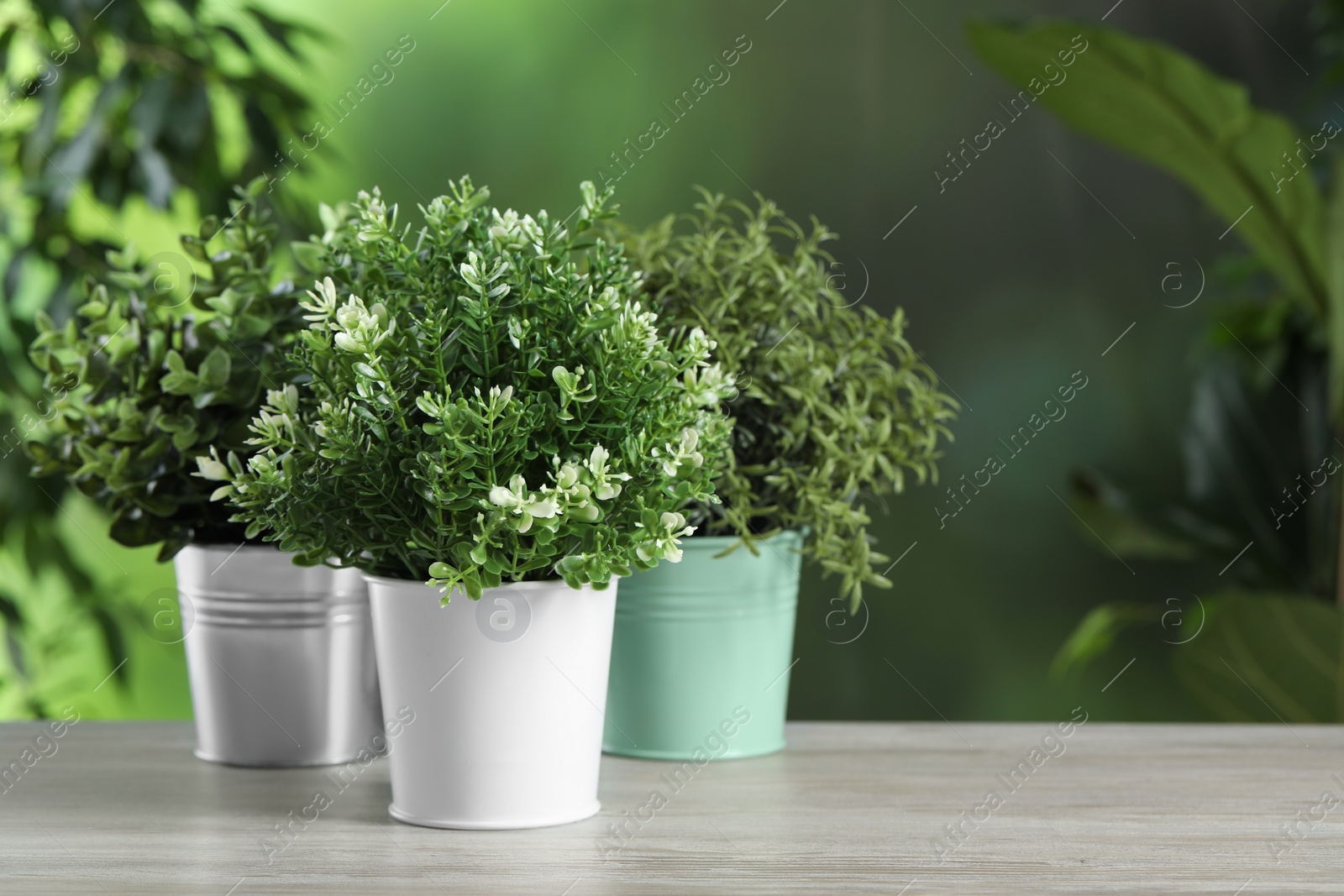 Photo of Different artificial potted herbs on white wooden table outdoors, space for text