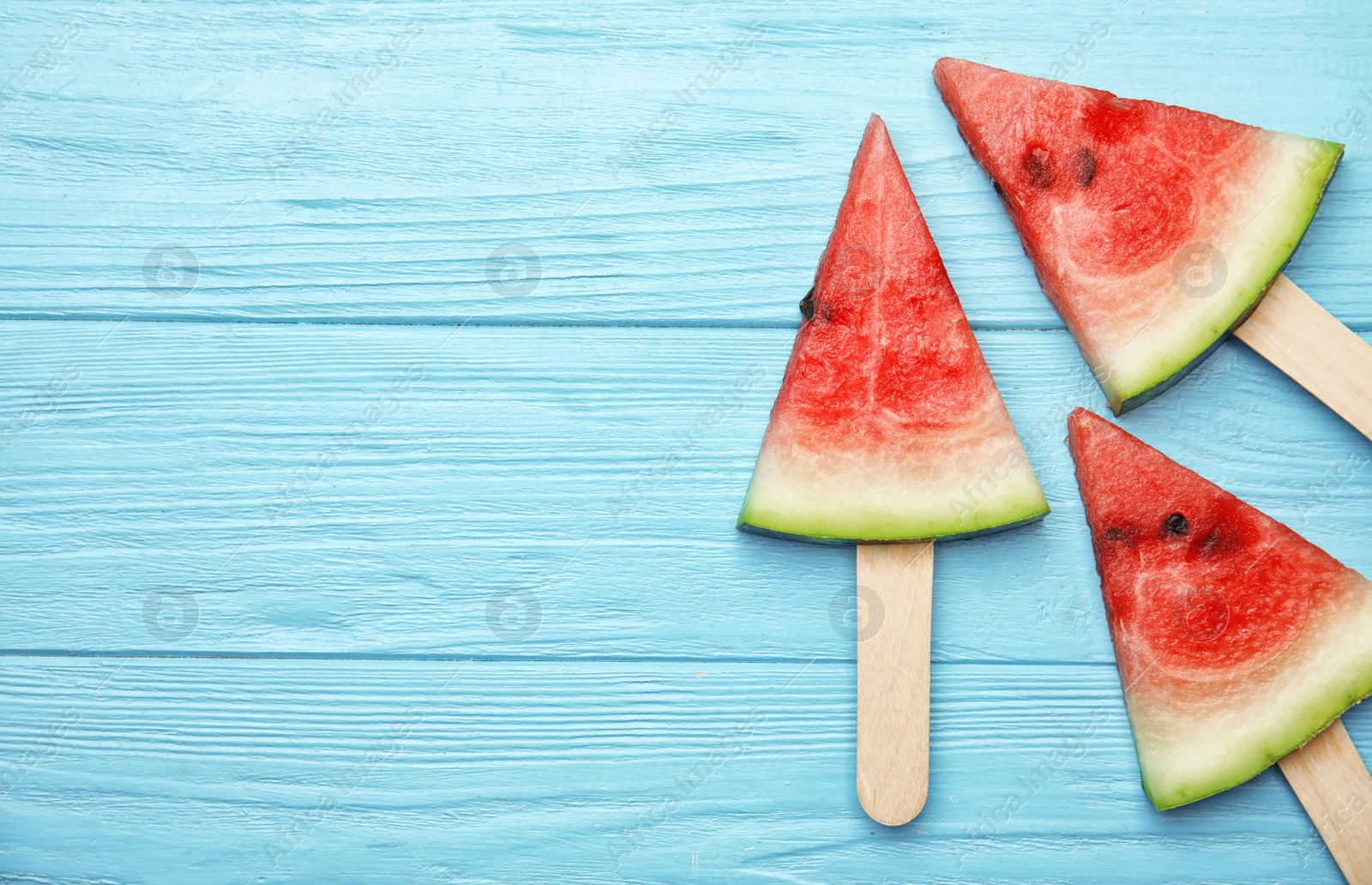 Photo of Watermelon popsicles on wooden background, top view