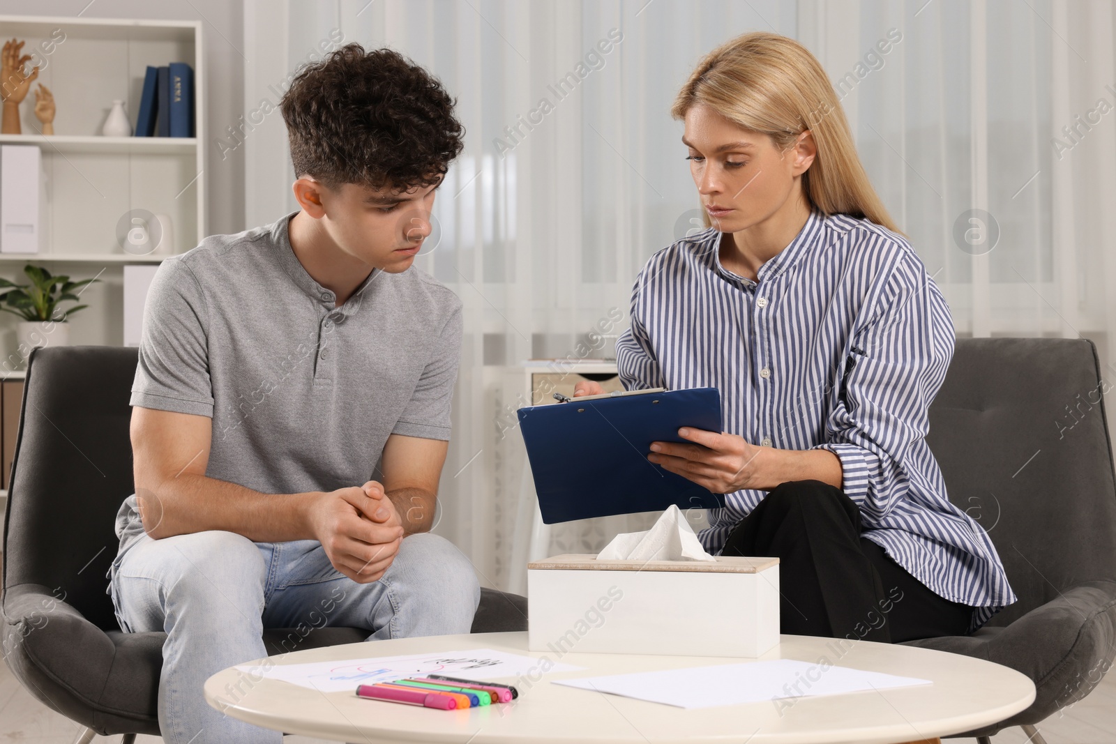 Photo of Psychologist working with teenage boy in office. Teenager problems