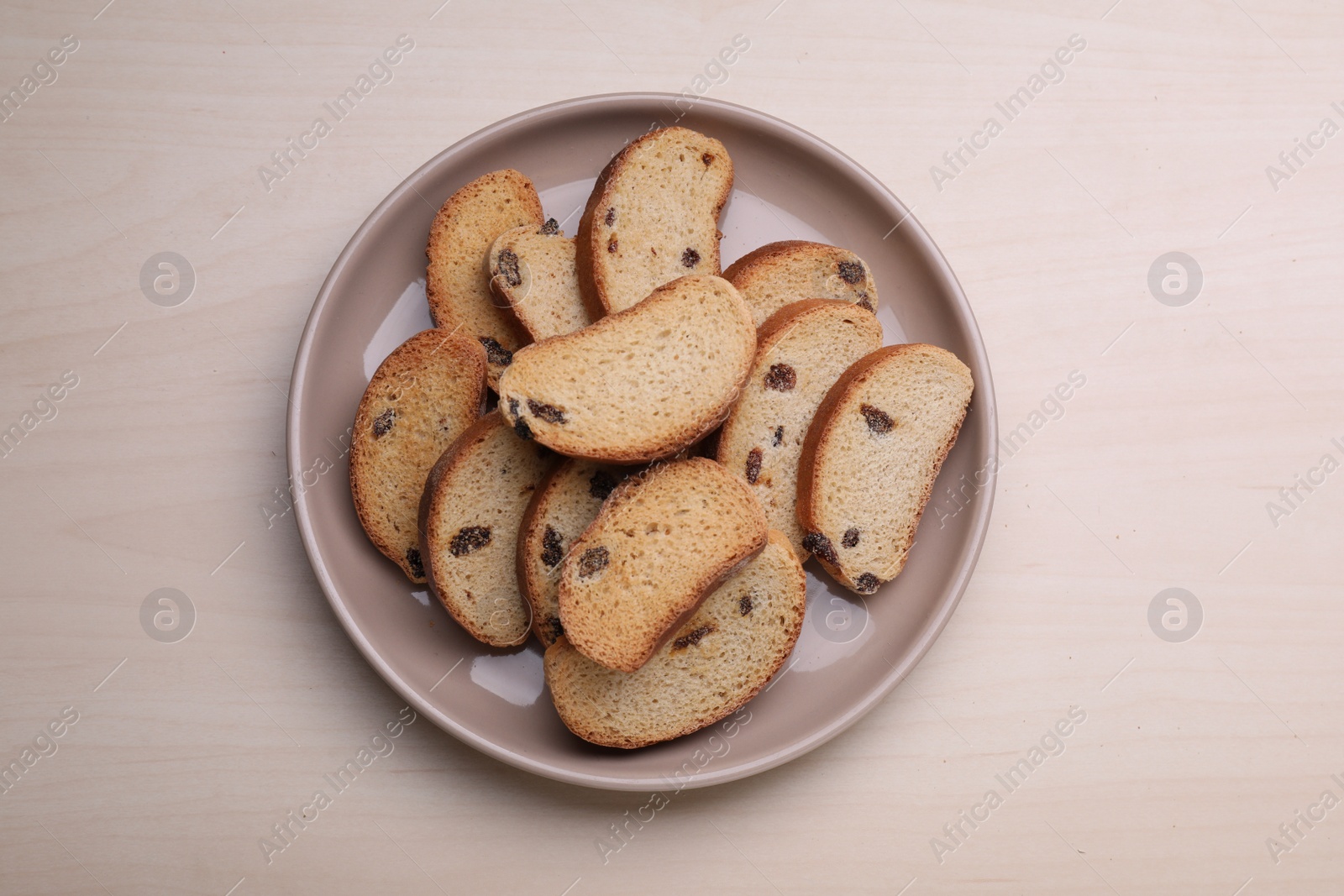 Photo of Plate of sweet hard chuck crackers with raisins on wooden table, top view