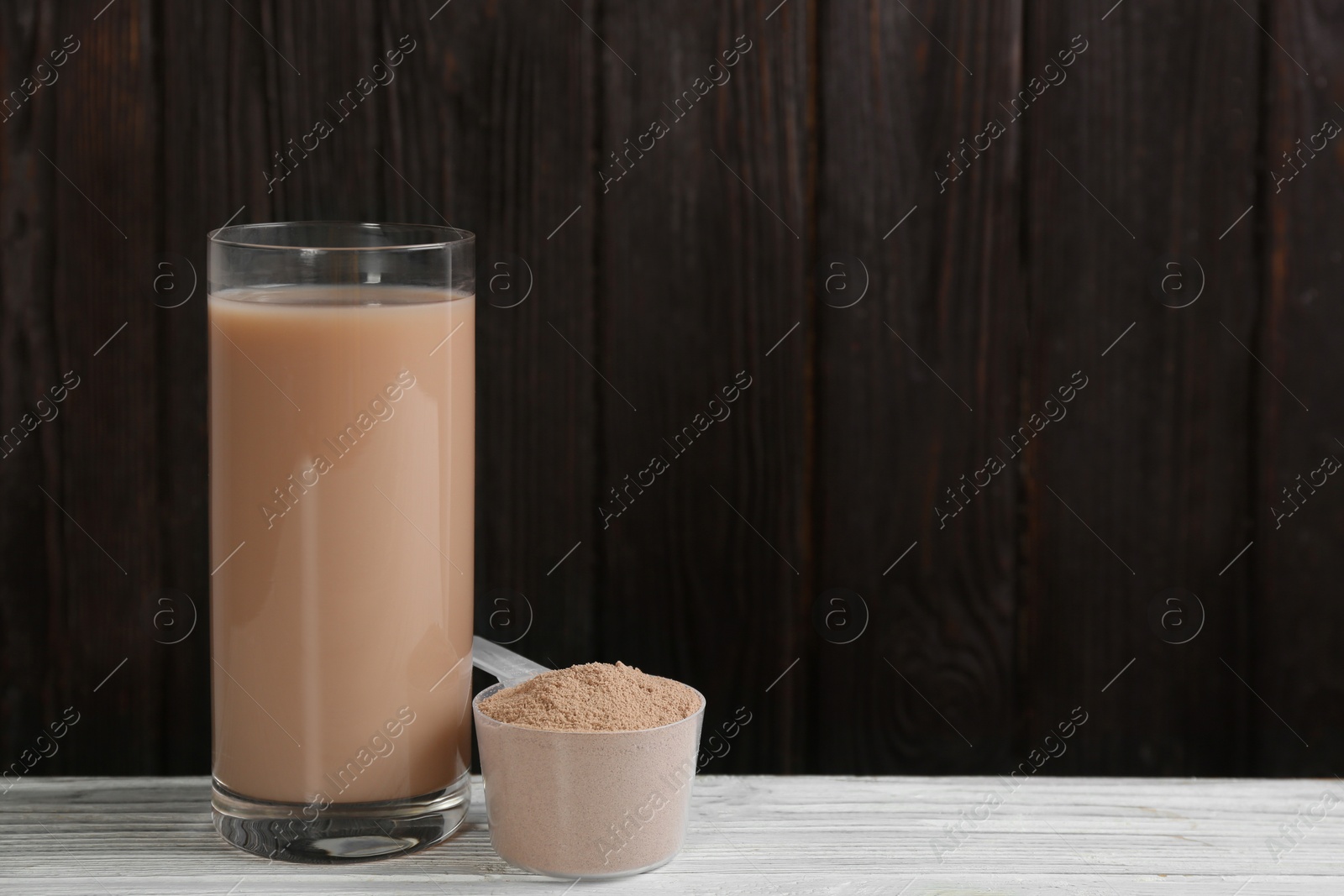 Photo of Protein shake and powder on white wooden table, space for text