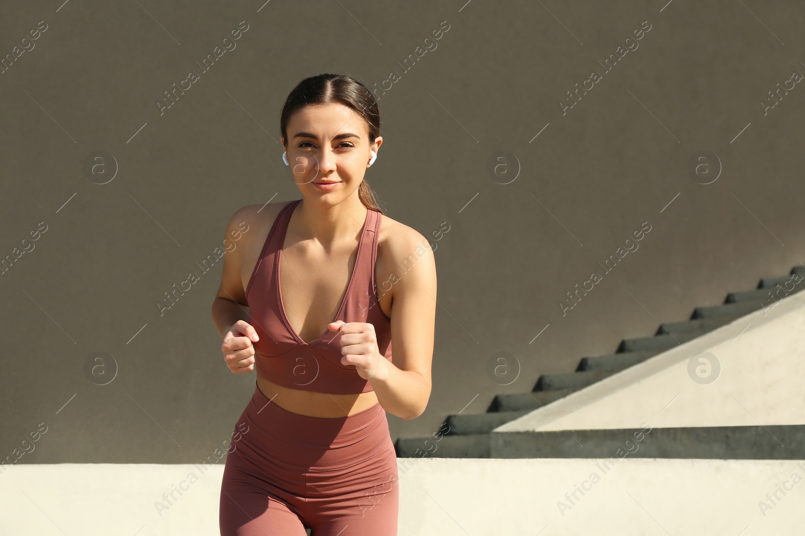 Photo of Young woman in stylish sports wear running outdoors