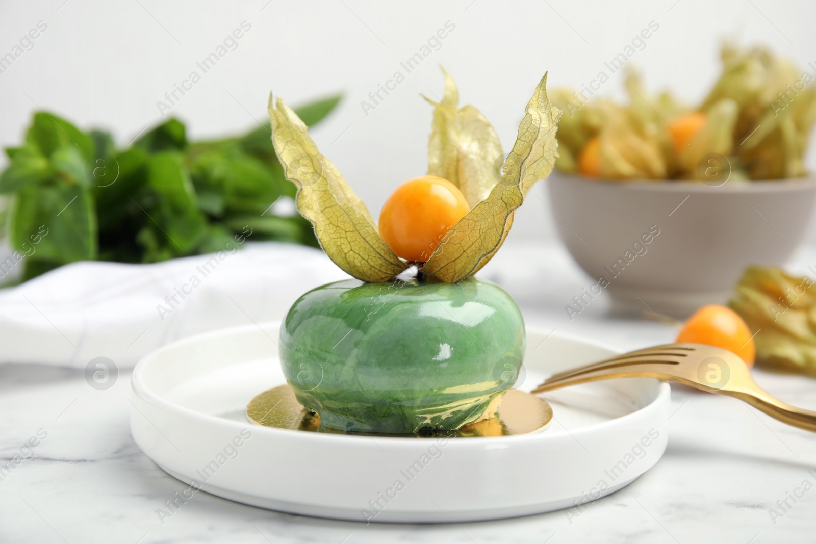 Photo of Delicious mousse cake decorated with physalis fruit on white marble table