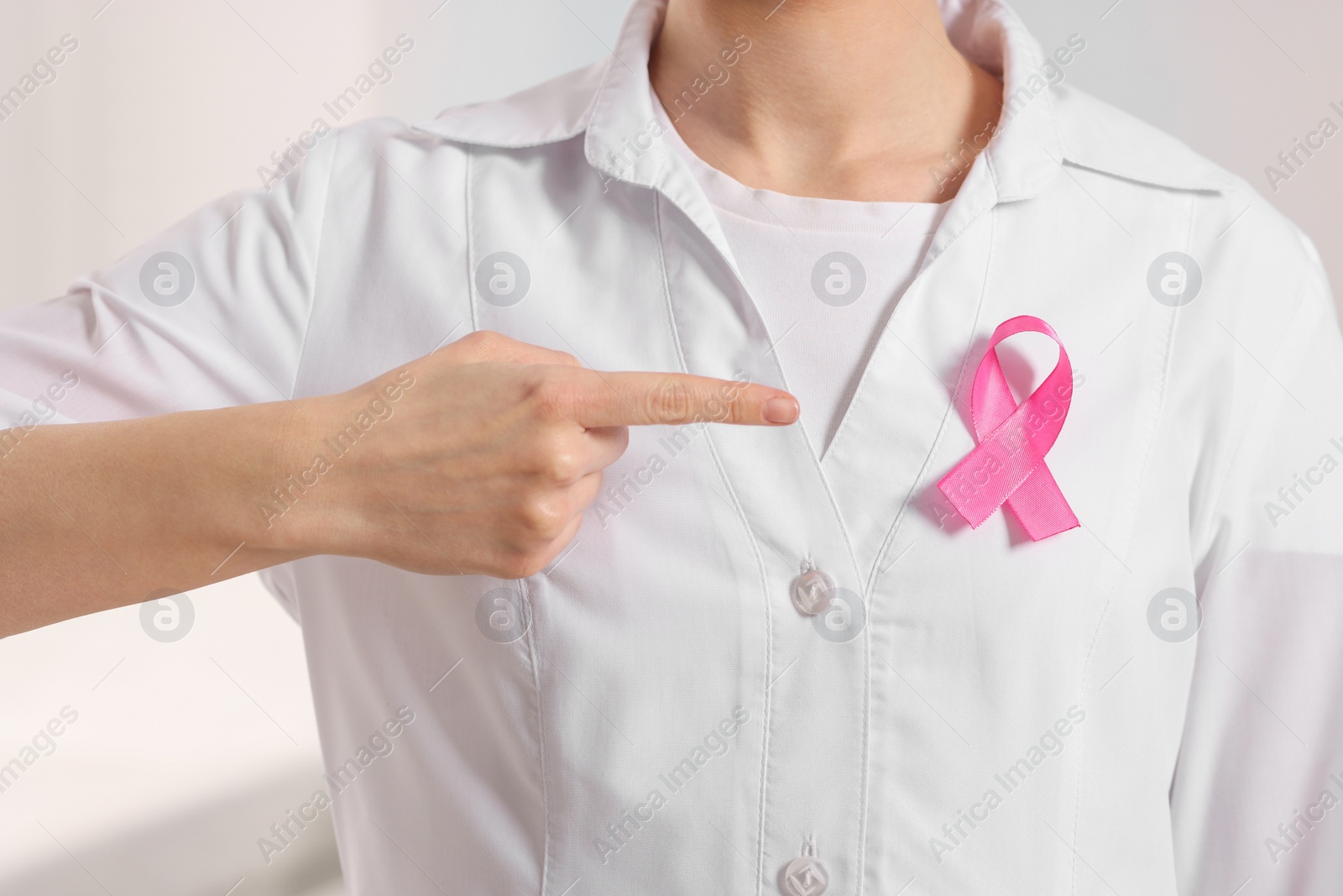 Photo of Mammologist pointing at pink ribbon in hospital, closeup. Breast cancer awareness