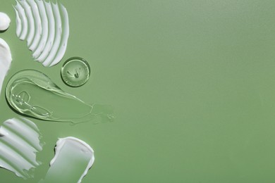 Samples of face cream on green background, top view. Space for text