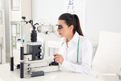 Female children's doctor working with ophthalmic equipment in office