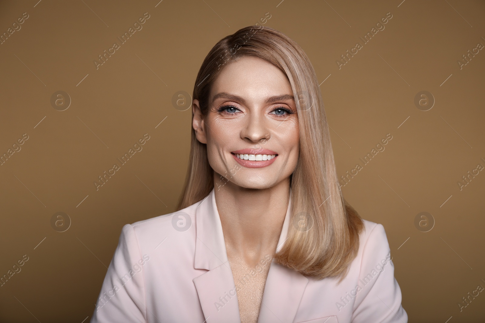 Image of Portrait of stylish attractive woman with blonde hair smiling on pastel brown background