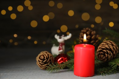Photo of Burning candle and Christmas decor on wooden table against blurred festive lights, space for text 
