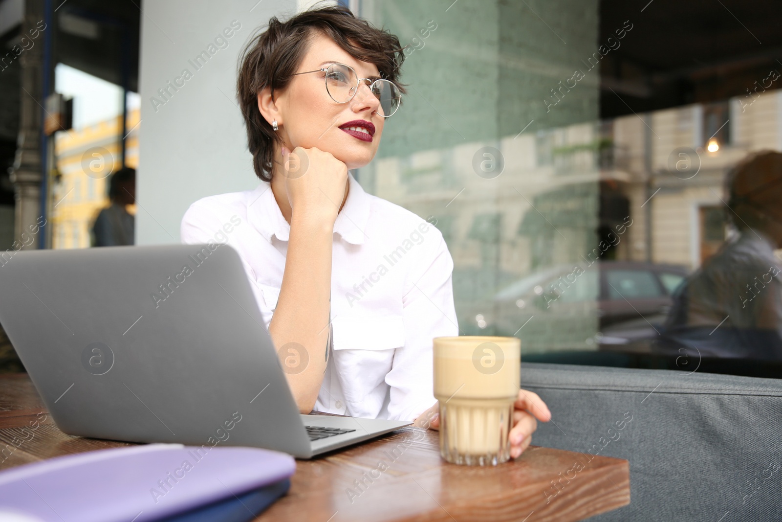 Photo of Young woman working with laptop at desk in cafe