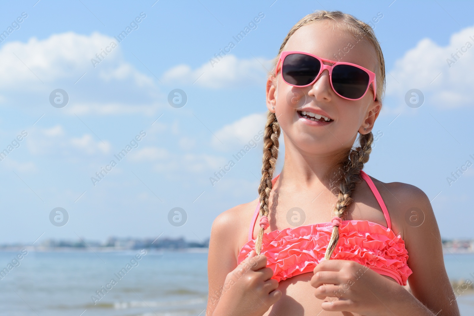 Photo of Little girl wearing sunglasses at beach on sunny day. Space for text