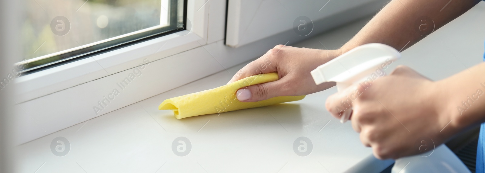 Image of Woman cleaning window sill with rag and detergent indoors, closeup. Banner design