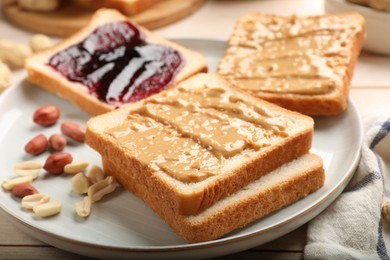 Photo of Delicious toasts with peanut butter, jam and nuts on table, closeup