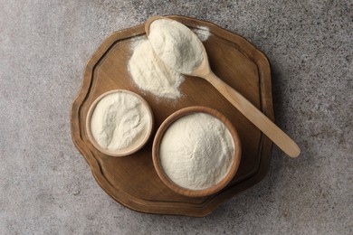 Bowls and spoon of agar-agar powder on grey table, top view