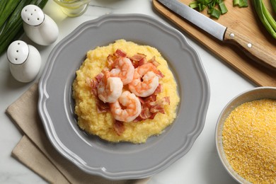 Photo of Plate with fresh tasty shrimps, bacon, grits and green onion on white marble table, flat lay