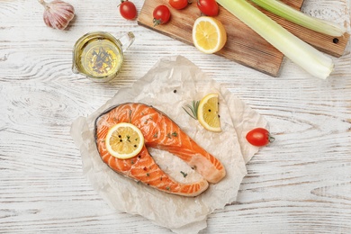 Photo of Fresh raw salmon steak with lemon and pepper on wooden table, top view