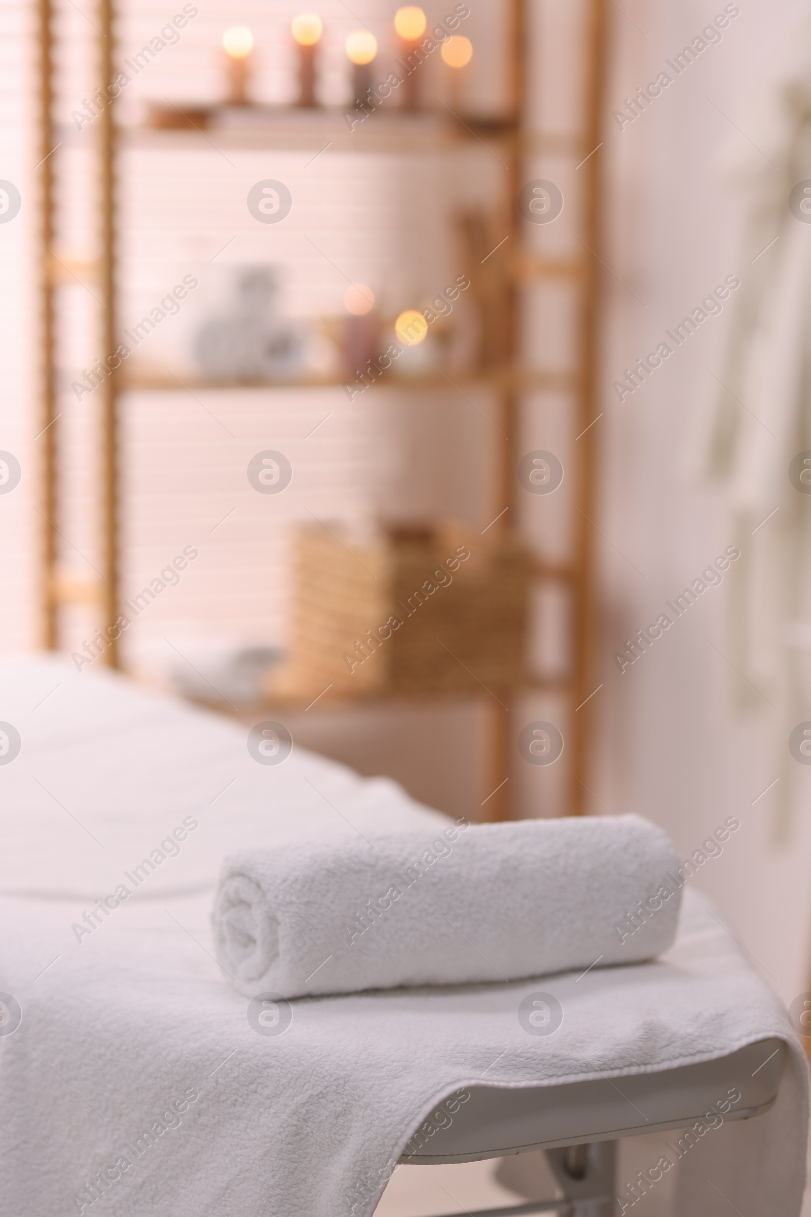 Photo of Rolled towel on massage table in spa center. Space for text